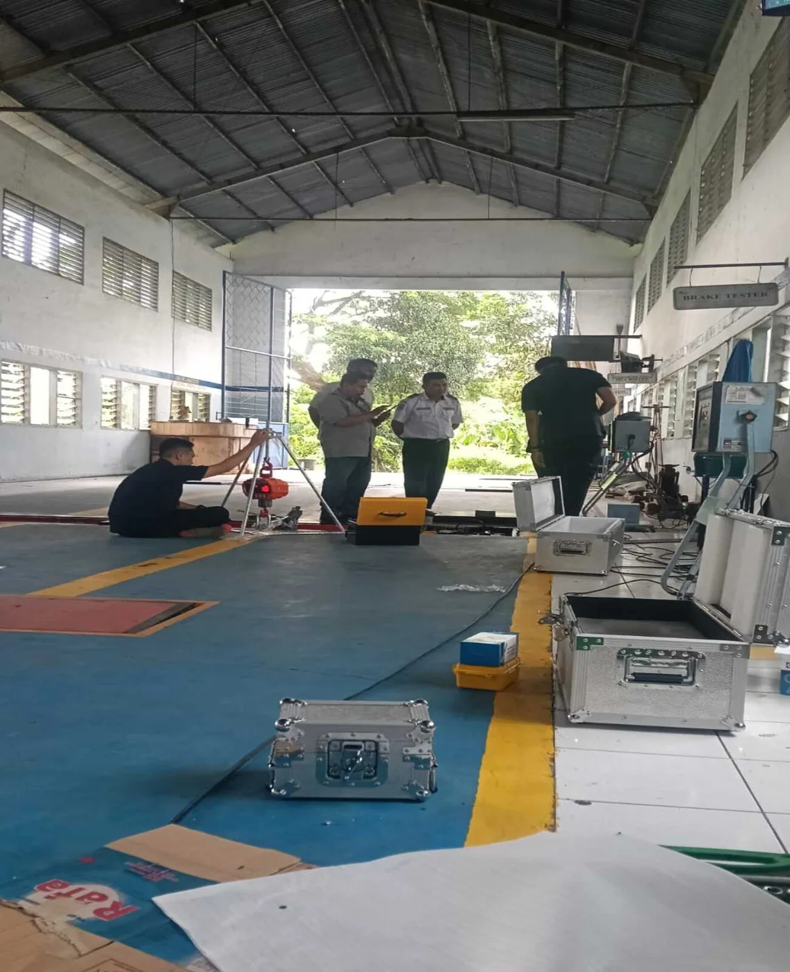 Tim menyiapkan perangkat kalibrasi bersama petugas di area pengujian kendaraan.